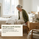Frau ab 60 sitzt morgens auf der Bettkante und startet mit einer Karte der Silver Moments Cards Morgen- & Abendroutine in den Tag