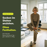 Frau ab 50 zieht Socken im Stehen an – gutes Gleichgewicht im Alltag