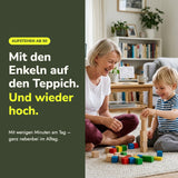 Frau ab 60 spielt mit ihren Enkeln auf dem Teppich – wieder sicher vom Boden aufstehen mit Silver Moments Cards