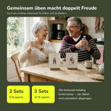 Paar ab 60 übt lachend am Küchentisch mit Wasserflaschen als Gewichte – Übungskarten Im Sitzen als Geschenk, Mengenrabatt ab 2 Sets